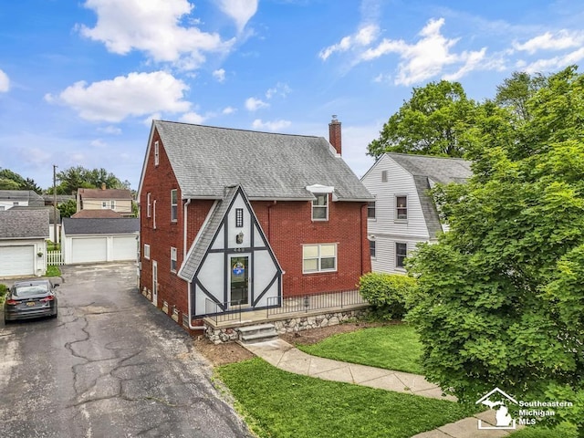 448 Borgess Ave, Monroe, MI 48162 - tudor house with brick siding, a chimney, a shingled roof, a front lawn, and a detached garage