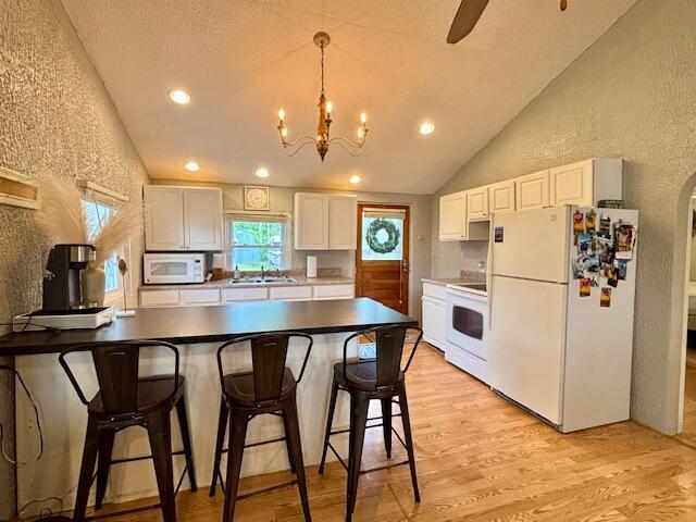 824 N Werners Landing Dr, Bronson, MI 49028 - kitchen featuring white appliances, lofted ceiling, a peninsula, a textured wall, and light wood-style floors