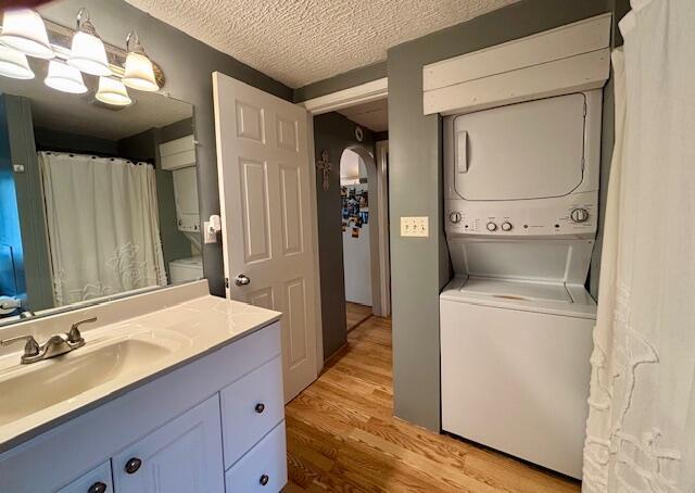 824 N Werners Landing Dr, Bronson, MI 49028 - full bath featuring stacked washer / drying machine, wood finished floors, vanity, toilet, and a textured ceiling