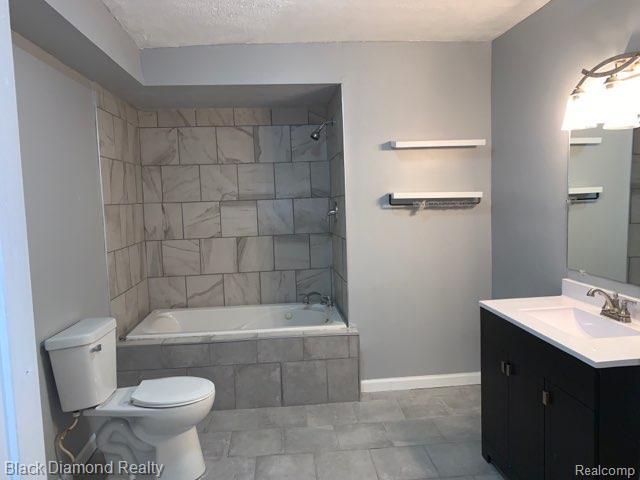 18499 Gruebner St, Detroit, MI 48234 - full bathroom with toilet, vanity, baseboards, tiled shower / bath, and a textured ceiling