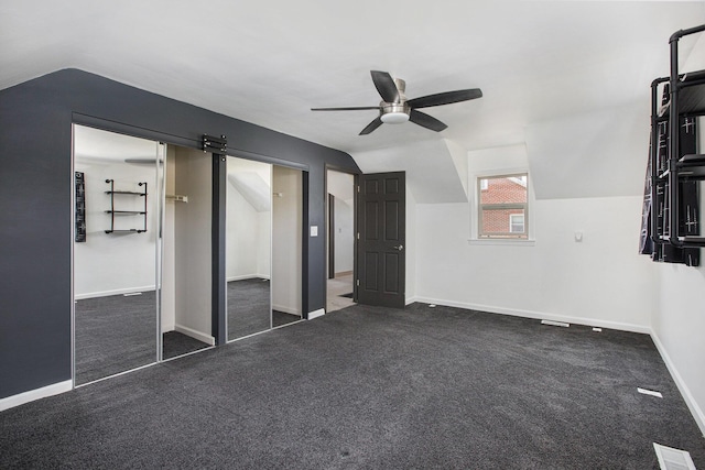 525 Riverview Ave, Monroe, MI 48162 - unfurnished bedroom with vaulted ceiling, baseboards, ceiling fan, carpet flooring, and a barn door