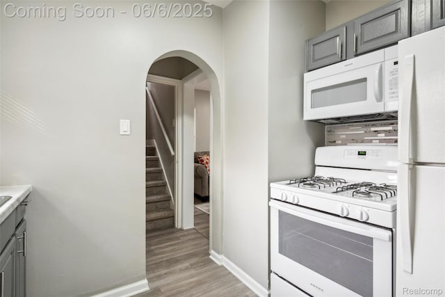 1512 Marion Ave, Lincoln Park, MI 48146 - kitchen featuring white appliances, gray cabinetry, light wood-style floors, arched walkways, and baseboards