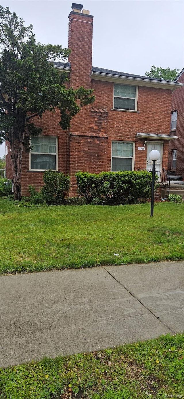 18966 Mendota St, Detroit, MI 48221 - view of front of house with a chimney, brick siding, and a front yard