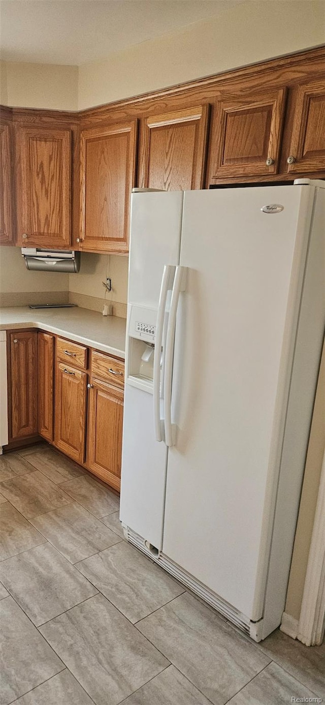 18966 Mendota St, Detroit, MI 48221 - kitchen with white fridge with ice dispenser, brown cabinetry, light countertops, and light tile patterned flooring