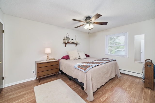 819 Elm St, Manistee, MI 49660 - bedroom with a baseboard radiator, light wood finished floors, ceiling fan, a textured ceiling, and baseboards