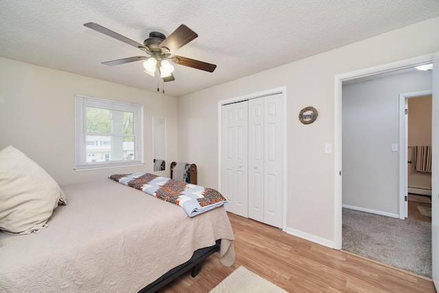 819 Elm St, Manistee, MI 49660 - bedroom featuring a baseboard radiator, light wood-style floors, a closet, ceiling fan, and baseboards