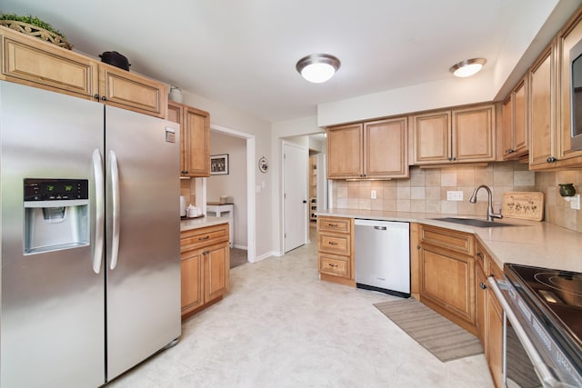 819 Elm St, Manistee, MI 49660 - kitchen featuring stainless steel appliances, a sink, backsplash, light countertops, and baseboards