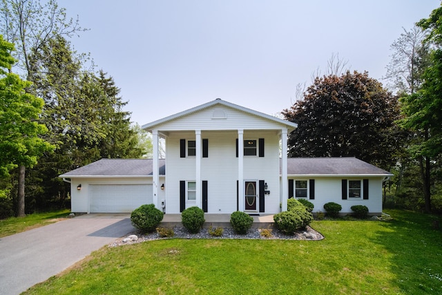 819 Elm St, Manistee, MI 49660 - greek revival inspired property with a porch, driveway, an attached garage, a front lawn, and a shingled roof