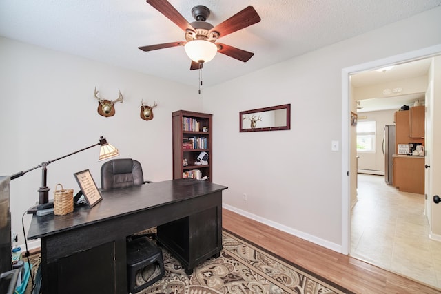 819 Elm St, Manistee, MI 49660 - office with a ceiling fan, baseboards, light wood-style floors, and a baseboard heating unit