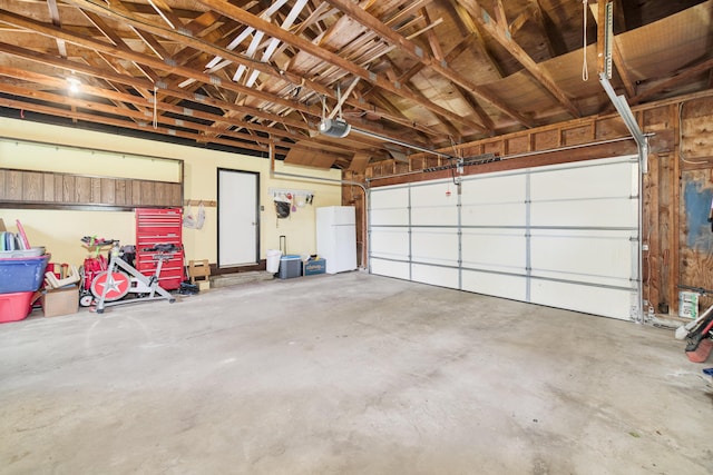 819 Elm St, Manistee, MI 49660 - garage featuring freestanding refrigerator and a garage door opener