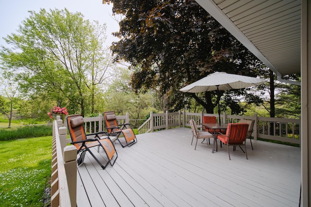 819 Elm St, Manistee, MI 49660 - wooden deck featuring outdoor dining area, a lawn, and view of wooded area
