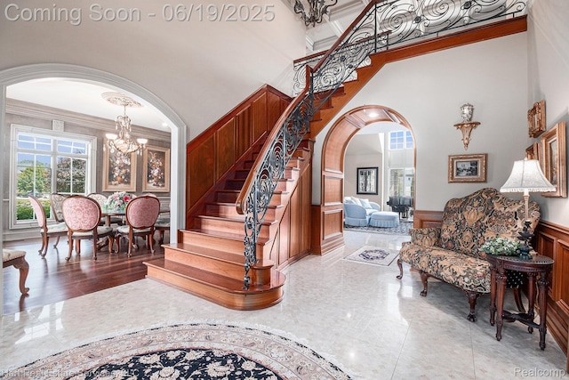 11384 Scarborough Dr, Shelby Twp, MI 48315 - stairs with a chandelier, a high ceiling, a wainscoted wall, ornamental molding, and arched walkways