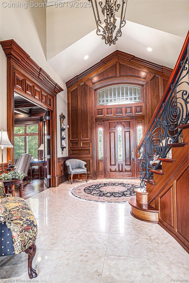 11384 Scarborough Dr, Shelby Twp, MI 48315 - foyer with a decorative wall, a chandelier, high vaulted ceiling, wooden walls, and stairway