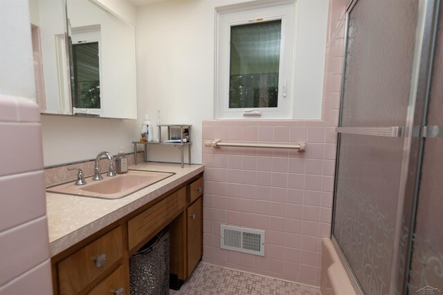 4680 Pinehaven Dr, Saginaw, MI 48638 - full bathroom featuring tile walls, vanity, tile patterned flooring, combined bath / shower with glass door, and wainscoting