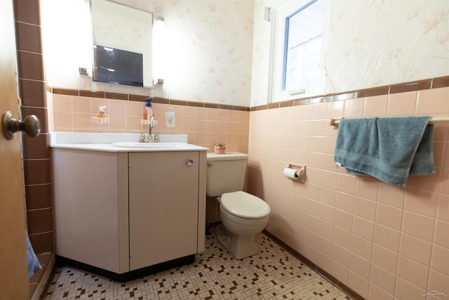 4680 Pinehaven Dr, Saginaw, MI 48638 - bathroom with tile walls, wallpapered walls, a wainscoted wall, toilet, and vanity