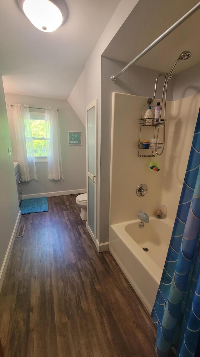 11390 Patterson Rd, Ravenna, MI 49451 - bathroom featuring wood finished floors, shower / bathtub combination with curtain, toilet, and baseboards