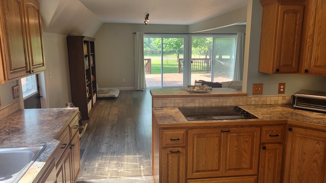 11390 Patterson Rd, Ravenna, MI 49451 - kitchen featuring black electric stovetop, healthy amount of natural light, brown cabinets, and lofted ceiling