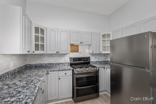 216 E Main St, Ionia, MI 48846 - kitchen featuring stainless steel appliances, glass insert cabinets, decorative backsplash, and dark stone counters