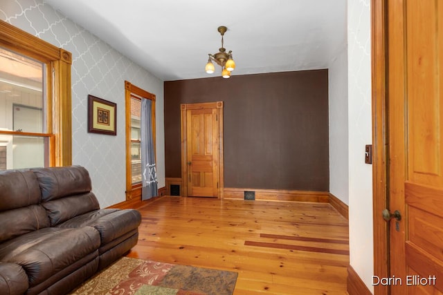 216 E Main St, Ionia, MI 48846 - living area with wallpapered walls, hardwood / wood-style flooring, baseboards, and a chandelier