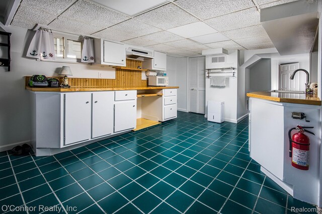 105 Gratiot Blvd, Marysville, MI 48040 - kitchen with white microwave, a sink, white cabinetry, baseboards, and a drop ceiling