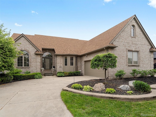 19996 Devonshire Ln, Sterling Heights, MI 48044 - french country home with roof with shingles, brick siding, driveway, and an attached garage