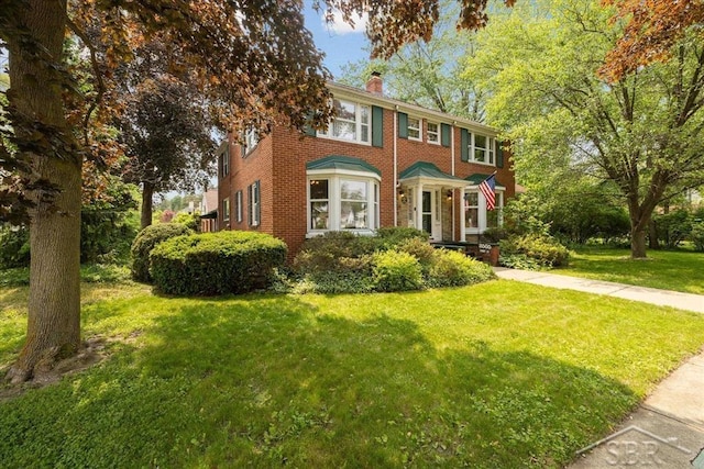 2505 Court St, Saginaw, MI 48602 - colonial inspired home with a chimney, brick siding, and a front yard