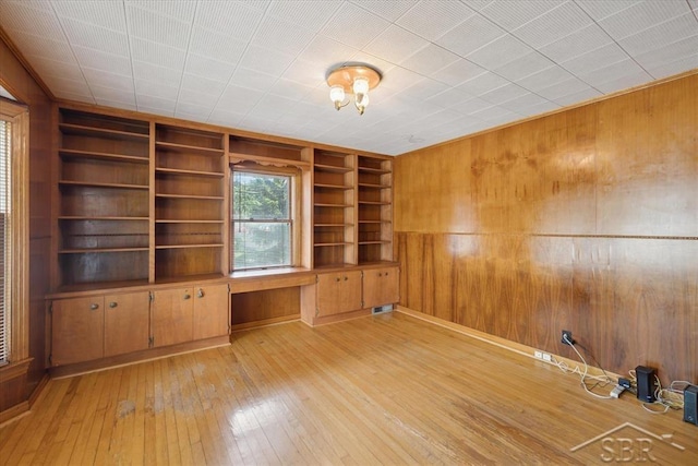 2505 Court St, Saginaw, MI 48602 - spare room with wood walls, built in shelves, and light wood-type flooring