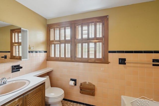 2505 Court St, Saginaw, MI 48602 - bathroom with tile walls, healthy amount of natural light, vanity, toilet, and a wainscoted wall