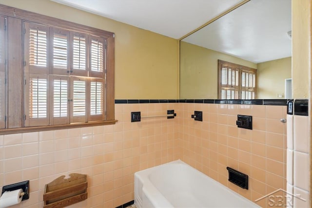 2505 Court St, Saginaw, MI 48602 - bathroom featuring tile walls, healthy amount of natural light, a bathtub, and wainscoting