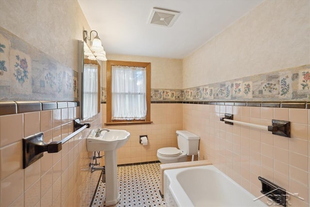 2505 Court St, Saginaw, MI 48602 - full bath featuring toilet, tile walls, a garden tub, wainscoting, and a sink