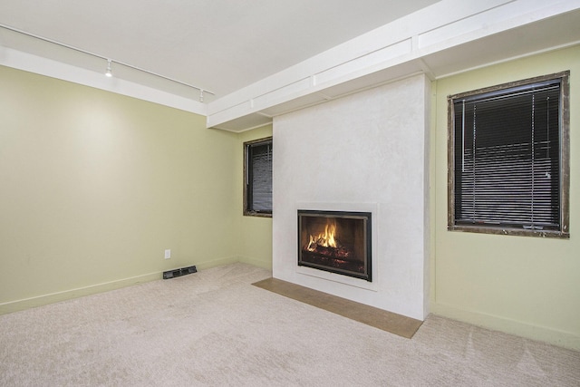 7362 30th St SE, Ada, MI 49301 - unfurnished living room featuring track lighting, a fireplace with flush hearth, carpet, and baseboards