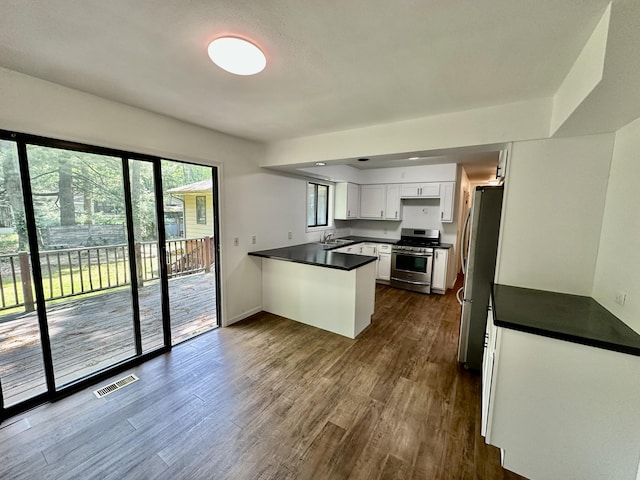 7362 30th St SE, Ada, MI 49301 - kitchen featuring appliances with stainless steel finishes, dark countertops, a peninsula, and white cabinets