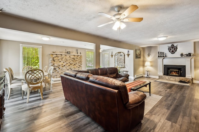 50902 Magician Lk Rd, Dowagiac, MI 49047 - living area with a textured ceiling, ceiling fan, a warm lit fireplace, baseboard heating, and wood finished floors