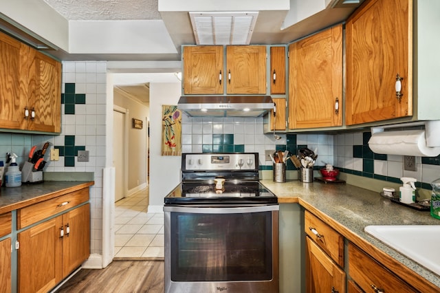 50902 Magician Lk Rd, Dowagiac, MI 49047 - kitchen with stainless steel electric stove, under cabinet range hood, backsplash, and brown cabinetry