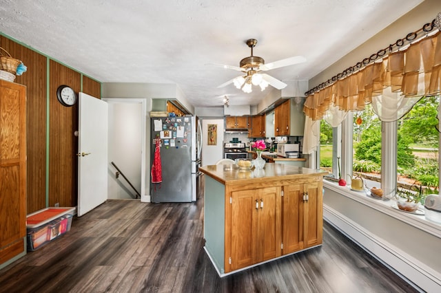 50902 Magician Lk Rd, Dowagiac, MI 49047 - kitchen featuring stainless steel appliances, a baseboard heating unit, brown cabinetry, dark wood-type flooring, and ceiling fan