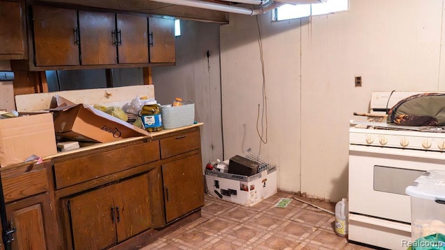 4107 Windward Dr, Lansing, MI 48911 - kitchen with white gas range, light floors, light countertops, and wooden walls