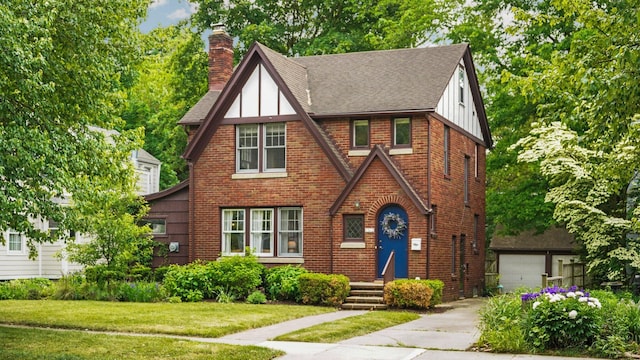 1512 Shadford Rd, Ann Arbor, MI 48104 - tudor house featuring a chimney, a shingled roof, brick siding, a front lawn, and board and batten siding