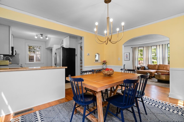 1512 Shadford Rd, Ann Arbor, MI 48104 - dining space featuring light wood finished floors, ornamental molding, a chandelier, arched walkways, and wainscoting