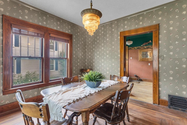 810 N Superior St, Albion, MI 49224 - dining area featuring wood finished floors, wallpapered walls, a chandelier, ornamental molding, and a textured ceiling