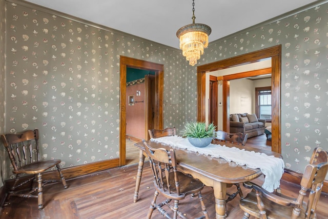 810 N Superior St, Albion, MI 49224 - dining room with wood finished floors, a chandelier, wallpapered walls, ornamental molding, and baseboards