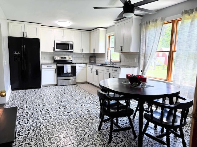 10073 Mcafee Dr, Montrose, MI 48457 - kitchen with appliances with stainless steel finishes, a sink, ceiling fan, dark countertops, and tasteful backsplash