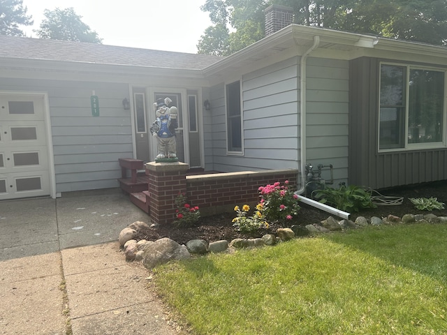 201 Goodell Ave, Colon, MI 49040 - view of property exterior with a chimney, concrete driveway, a shingled roof, and a lawn