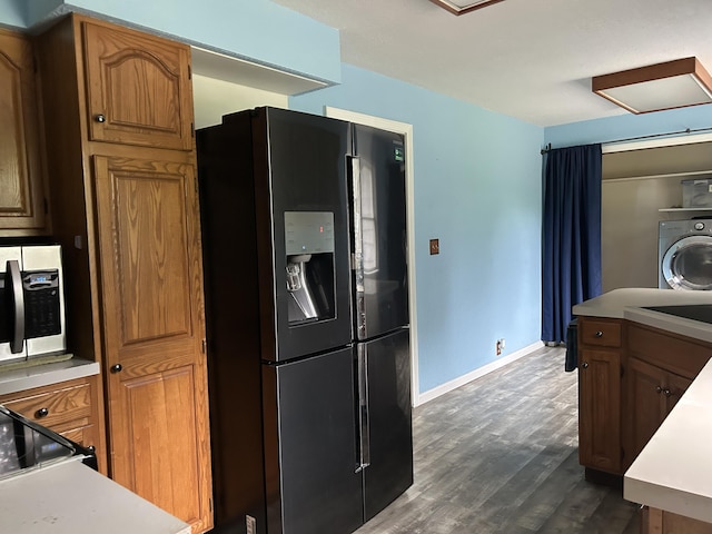 201 Goodell Ave, Colon, MI 49040 - kitchen featuring black fridge with ice dispenser, washer / clothes dryer, stainless steel microwave, dark wood-style floors, and light countertops