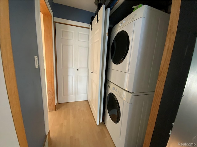 3255 Goodrich St, Ferndale, MI 48220 - laundry area featuring stacked washer and clothes dryer, light wood-type flooring, and a barn door