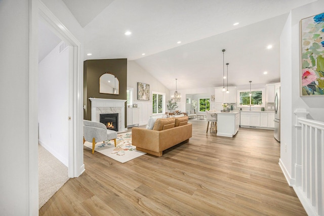 LOT166 Wren Ct, Caledonia, MI 49316 - living area featuring a fireplace, light wood-style floors, recessed lighting, a chandelier, and high vaulted ceiling