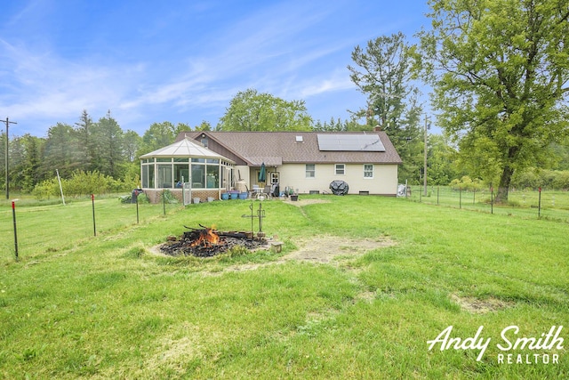 9386 N Vandecar Rd, Farwell, MI 48622 - rear view of house with a sunroom, a fire pit, and solar panels