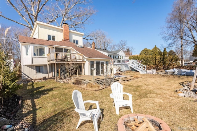 2830 N Duck Lake Rd, Highland, MI 48356 - back of house featuring an outdoor fire pit, a chimney, a wooden deck, a lawn, and roof with shingles