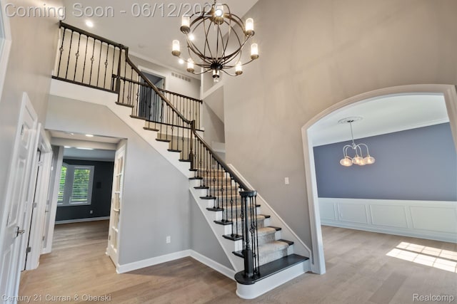 44251 Deep Hollow Cir, Northville, MI 48168 - staircase featuring a chandelier, wood finished floors, arched walkways, a towering ceiling, and baseboards