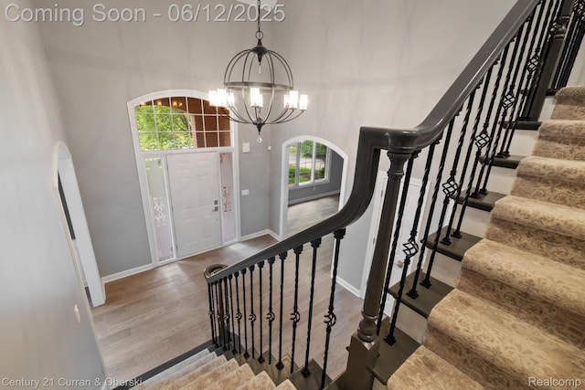 44251 Deep Hollow Cir, Northville, MI 48168 - entryway featuring wood finished floors, a chandelier, baseboards, a towering ceiling, and stairs