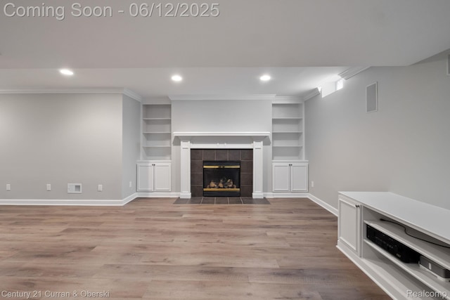 44251 Deep Hollow Cir, Northville, MI 48168 - unfurnished living room featuring baseboards, wood finished floors, recessed lighting, built in features, and a tiled fireplace